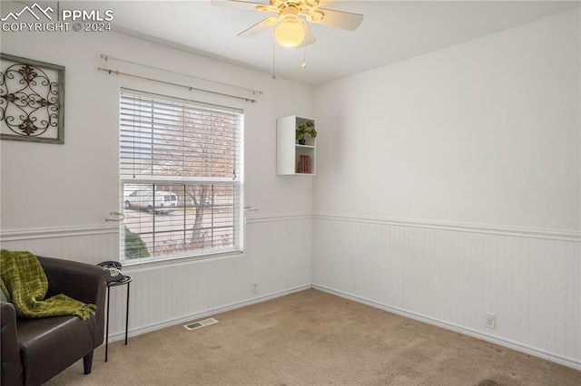 living area featuring light colored carpet and ceiling fan