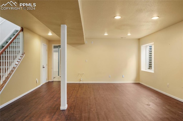 basement featuring a textured ceiling and dark hardwood / wood-style floors