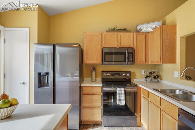 kitchen featuring sink, stainless steel appliances, lofted ceiling, light brown cabinetry, and light tile patterned floors