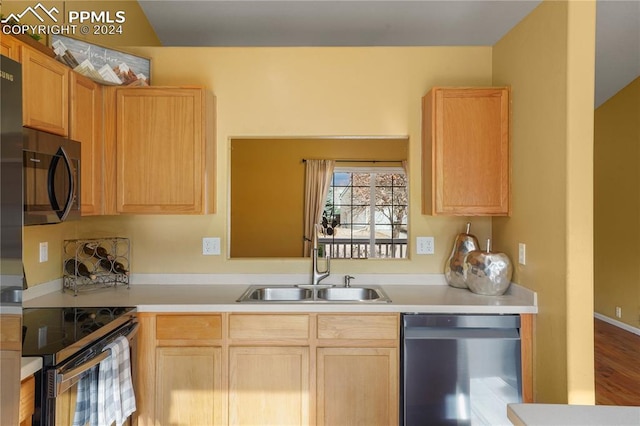 kitchen with light brown cabinetry, stainless steel appliances, hardwood / wood-style flooring, and sink