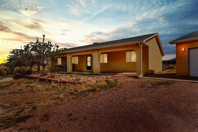 back house at dusk with a patio area