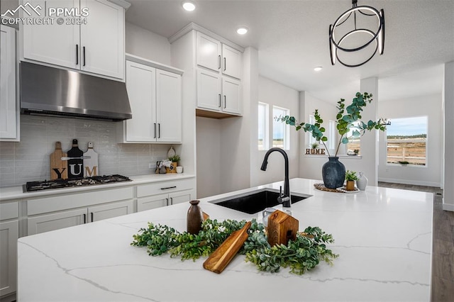 kitchen with white cabinets, light stone counters, stainless steel gas cooktop, and sink