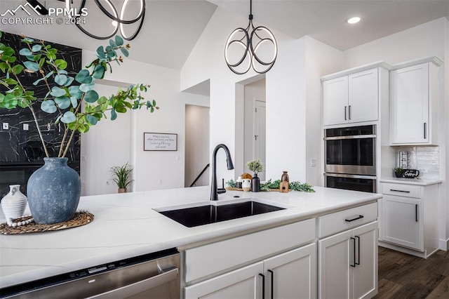 kitchen with appliances with stainless steel finishes, white cabinetry, a notable chandelier, and sink