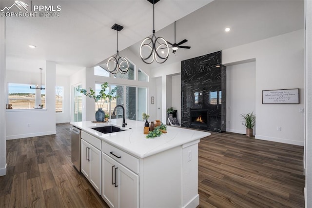 kitchen with a center island with sink, sink, dark hardwood / wood-style floors, a fireplace, and white cabinetry