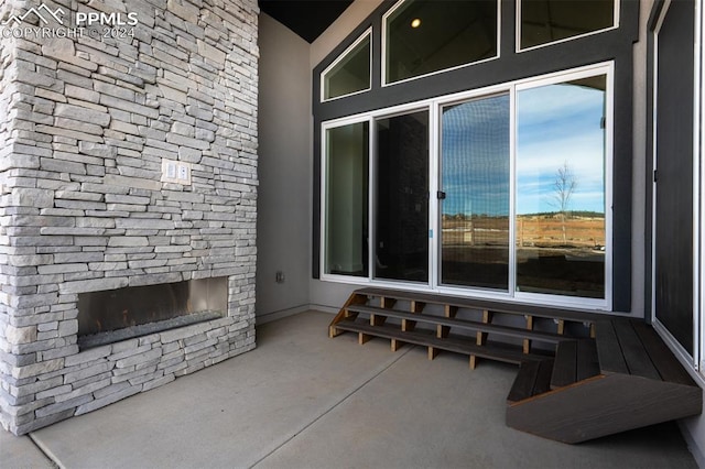 living room with high vaulted ceiling, concrete floors, and an outdoor stone fireplace