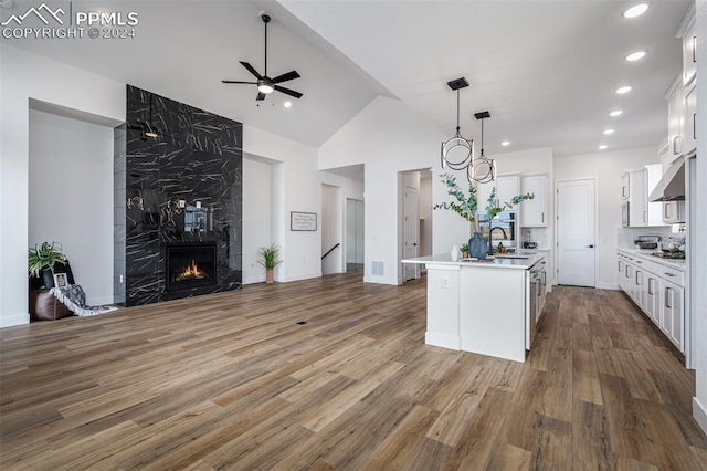 kitchen featuring white cabinets, a center island with sink, sink, hardwood / wood-style flooring, and a fireplace