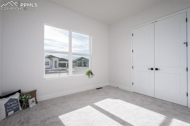 unfurnished bedroom featuring light carpet and a closet