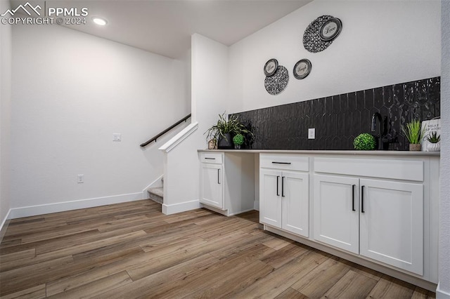 bar featuring light hardwood / wood-style floors, white cabinetry, and sink