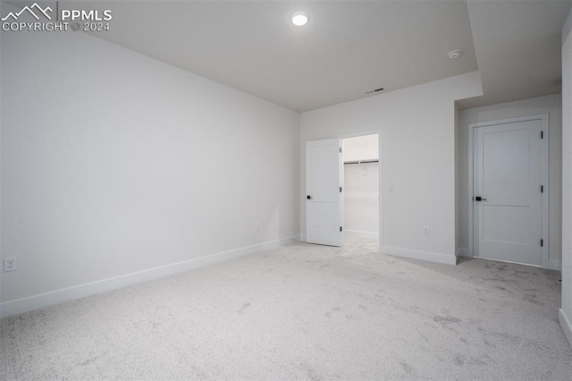 unfurnished bedroom featuring light colored carpet, a walk in closet, and a closet