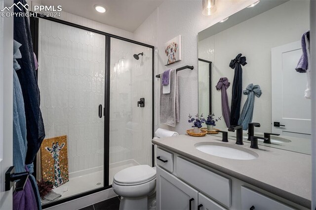 bathroom with vanity, a shower with shower door, and toilet