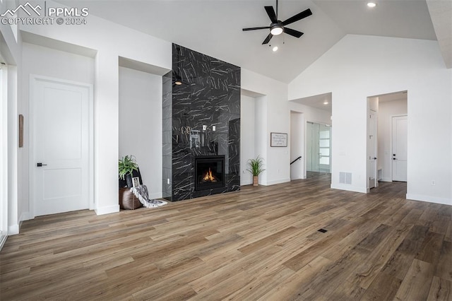 unfurnished living room with wood-type flooring, high vaulted ceiling, ceiling fan, and a premium fireplace