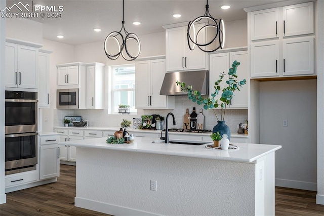 kitchen featuring a kitchen island with sink, hanging light fixtures, appliances with stainless steel finishes, white cabinetry, and extractor fan