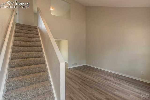 stairway featuring hardwood / wood-style floors and high vaulted ceiling