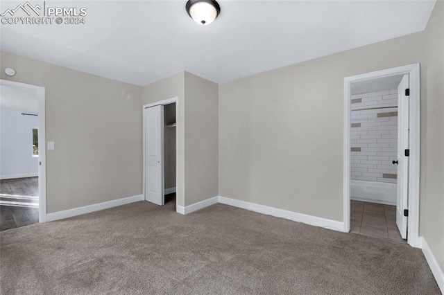 unfurnished bedroom featuring carpet, ensuite bath, and a closet