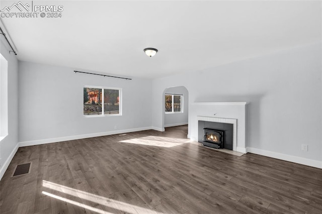 unfurnished living room featuring a tile fireplace and dark hardwood / wood-style flooring