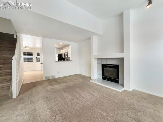 unfurnished living room featuring a tile fireplace and light carpet