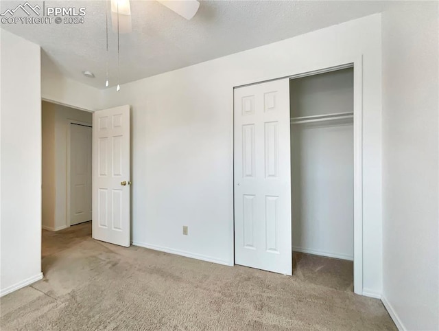 unfurnished bedroom featuring ceiling fan, light colored carpet, a textured ceiling, and a closet