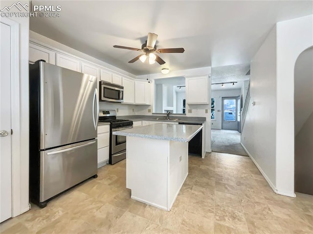 kitchen featuring ceiling fan, sink, stainless steel appliances, a kitchen island, and white cabinets