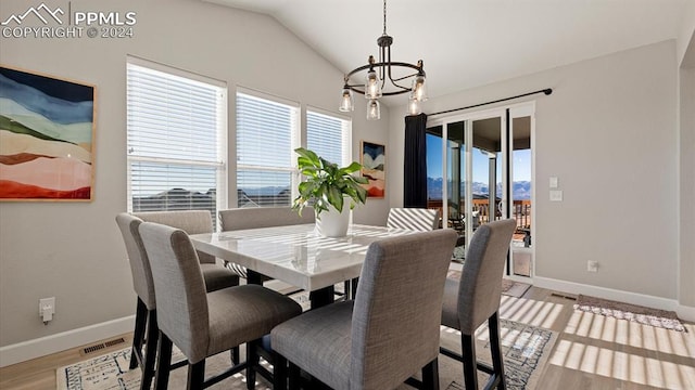 dining area with a notable chandelier, vaulted ceiling, and light wood-type flooring