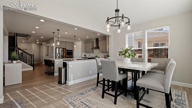 dining space featuring light hardwood / wood-style flooring, a chandelier, vaulted ceiling, and sink