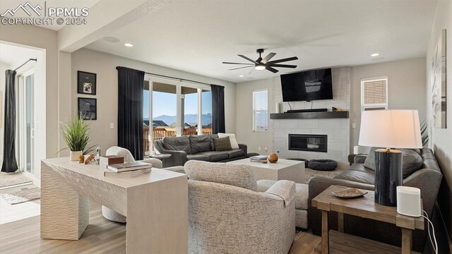 living room featuring a fireplace, ceiling fan, and light hardwood / wood-style flooring