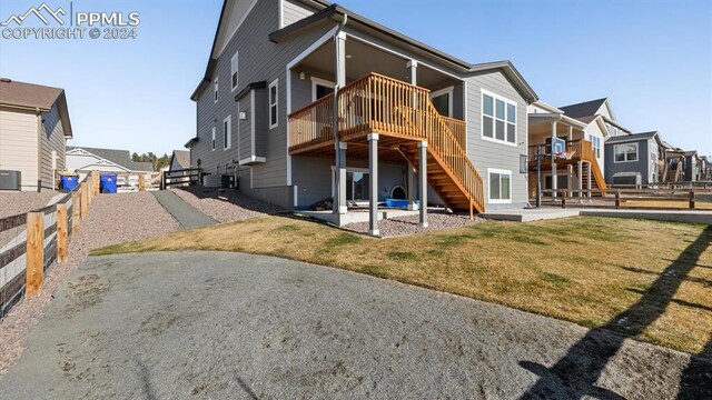 rear view of property featuring a yard, a deck, central AC unit, and a patio area