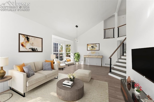 living room with hardwood / wood-style floors and high vaulted ceiling