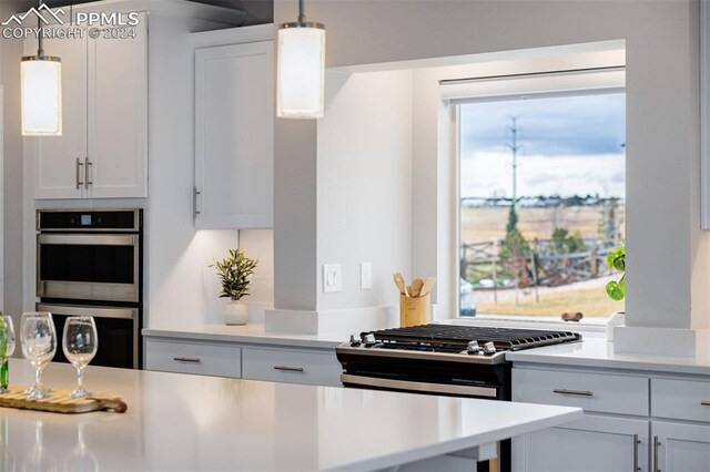 kitchen featuring white cabinets, stainless steel double oven, hanging light fixtures, and range with gas stovetop