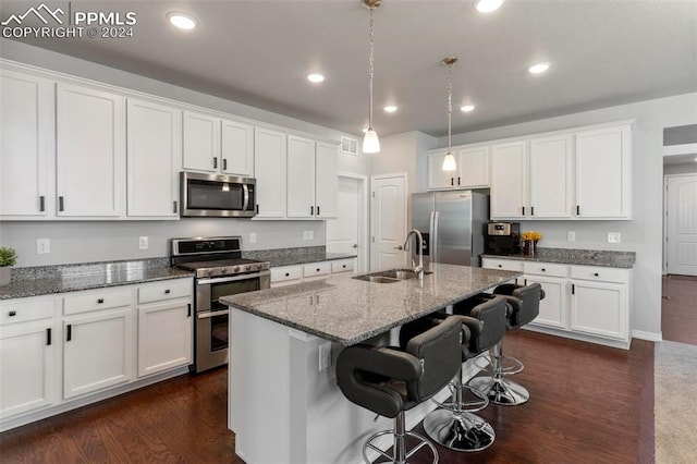 kitchen with sink, an island with sink, a kitchen bar, white cabinetry, and stainless steel appliances