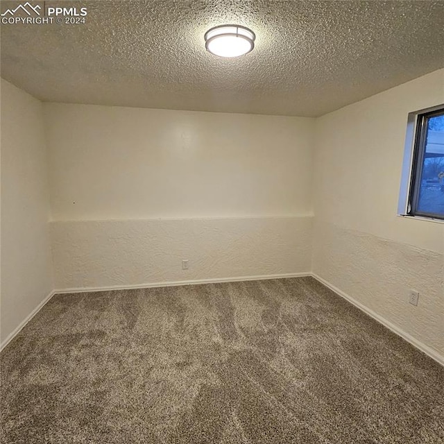 carpeted spare room with a textured ceiling