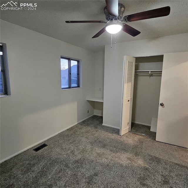 unfurnished bedroom with dark colored carpet, a closet, and ceiling fan