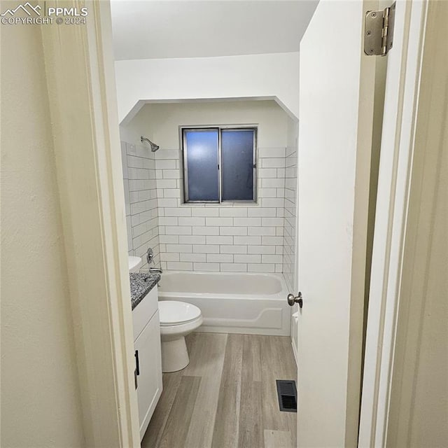 full bathroom with hardwood / wood-style flooring, vanity, toilet, and tiled shower / bath