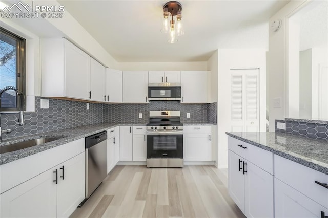 kitchen with appliances with stainless steel finishes, sink, white cabinets, and light stone counters