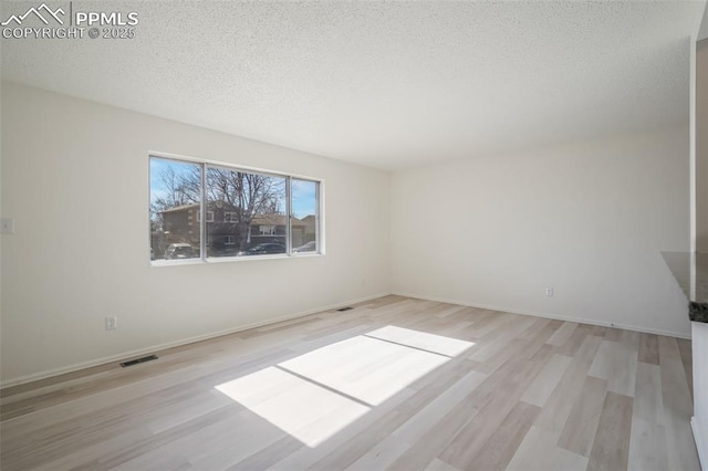 unfurnished room featuring light hardwood / wood-style floors and a textured ceiling