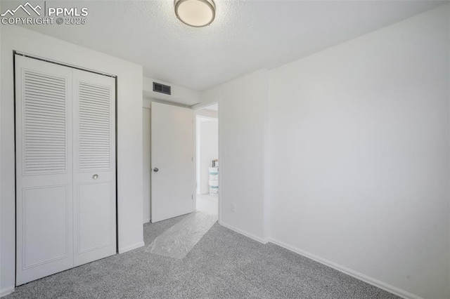 unfurnished bedroom featuring light carpet, a closet, and a textured ceiling