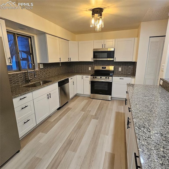 kitchen with white cabinets, sink, dark stone countertops, tasteful backsplash, and stainless steel appliances