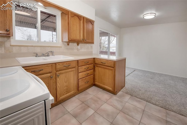 kitchen featuring backsplash, white range, sink, light colored carpet, and kitchen peninsula