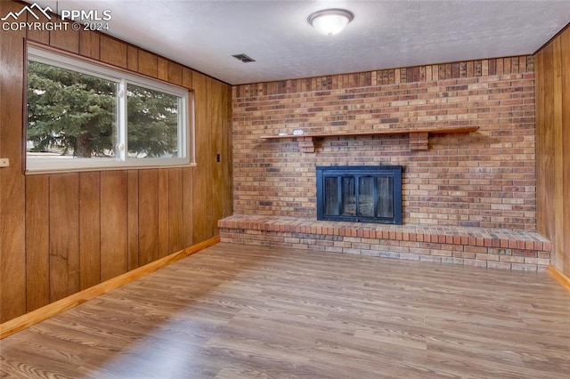 unfurnished living room featuring wooden walls, a fireplace, and hardwood / wood-style flooring