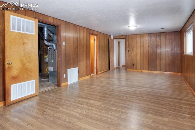 spare room featuring wooden walls and light hardwood / wood-style flooring