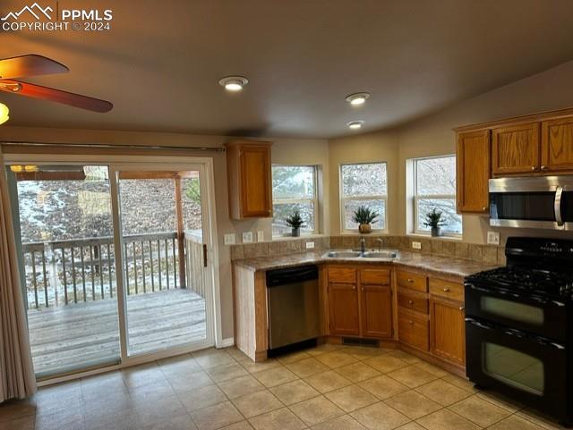 kitchen with stainless steel appliances, ceiling fan, sink, light tile patterned floors, and lofted ceiling