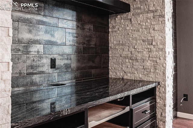 bar with dark hardwood / wood-style flooring and dark stone counters