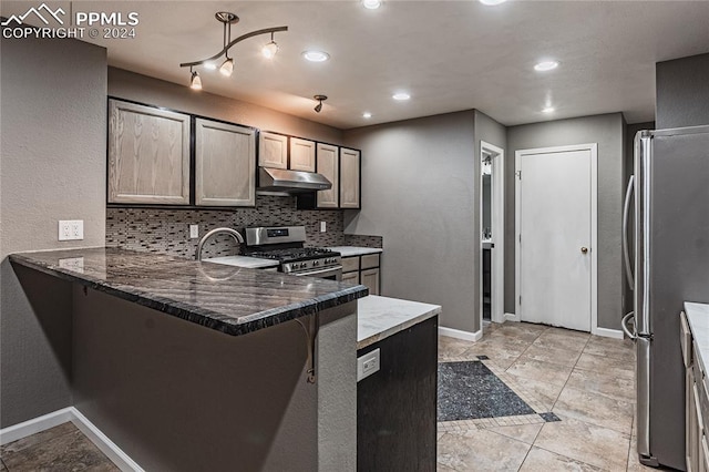 kitchen featuring stainless steel appliances, backsplash, kitchen peninsula, dark stone countertops, and a kitchen bar