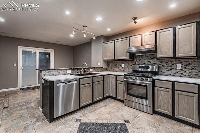 kitchen featuring kitchen peninsula, decorative backsplash, sink, and appliances with stainless steel finishes