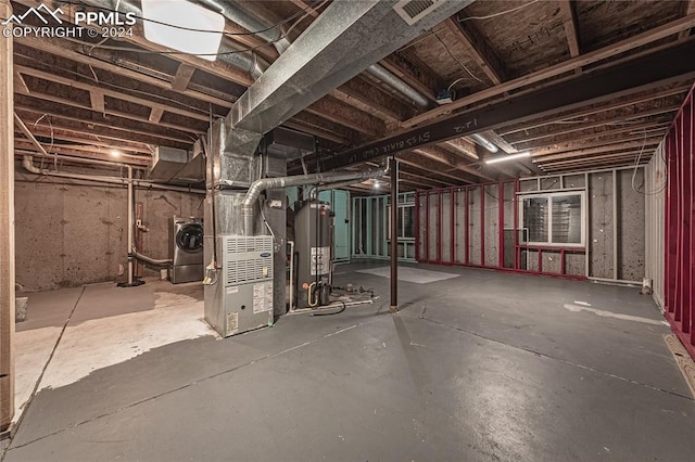 basement with heating unit, water heater, and washer / dryer