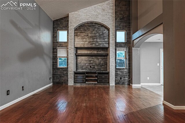 unfurnished living room with a wealth of natural light, high vaulted ceiling, and wood-type flooring