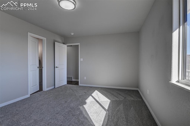 unfurnished bedroom featuring carpet flooring and multiple windows