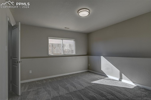 unfurnished room with dark carpet