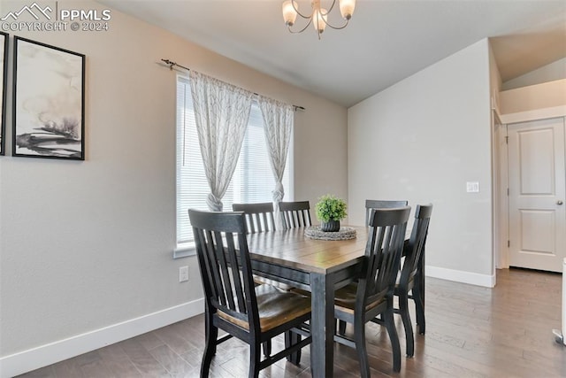 dining area with hardwood / wood-style flooring, a notable chandelier, and vaulted ceiling