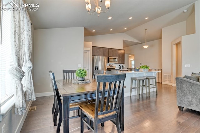 dining space featuring dark hardwood / wood-style floors, lofted ceiling, and an inviting chandelier