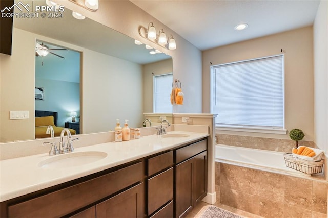 bathroom with tiled tub, ceiling fan, tile patterned flooring, and vanity